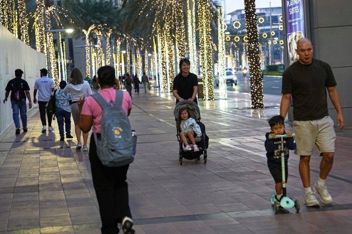 سقوط آرامش دبی؛ چگونه جنگ ایران تصویر لوکس خلیج فارس را بر هم زد؟ People walk along a main street in downtown Dubai.